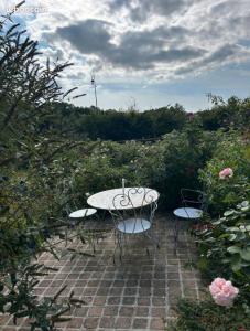 Una mesa y sillas en un patio de ladrillo con rosas. en Chambre privée au bord de la rivière, 
