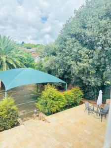 a patio with a blue umbrella and chairs and trees at DeRockview Lodge in Johannesburg +42 photos