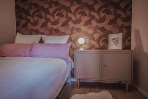 a bedroom with a bed with purple pillows and a wall at Im Prummehuck in Raeren