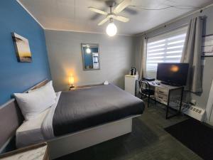a bedroom with a bed and a desk with a television at Motel Le Victo in Victoriaville