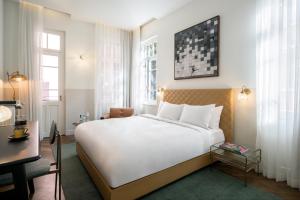 a hotel room with a large bed and a desk at Nordoy Hotel - Fattal Colors in Tel Aviv