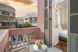 a balcony with a bed and a table with flowers at Nordoy Hotel - Fattal Colors in Tel Aviv +33 photos