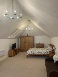 a bedroom with a bed and a couch in a attic at Charming King Bed Ensuite Studio in Peaceful West Challow in Wantage