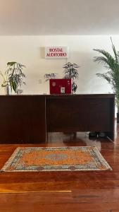 un bureau en bois avec un tapis dans une pièce avec des plantes dans l'établissement Hostal Auditorio, à Mexico