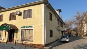 奇姆肯特Hostel Miras的一辆白色汽车停在一栋建筑物前