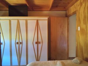 ein Schlafzimmer mit einem Bett und einem Fernseher an der Wand in der Unterkunft Cabaña los sauces in Chile Chico