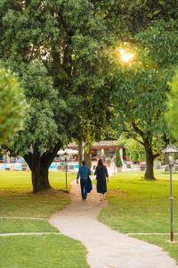 a man and woman walking down a path in a park at Borgo San Luigi in Monteriggioni