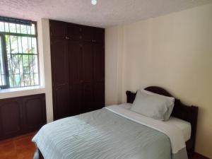 a bedroom with a bed with a wooden headboard and a window at Casa de hospedaje Lili - Cali in Cali