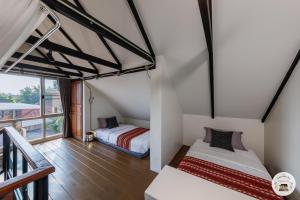 a attic bedroom with two beds and a balcony at Lannatika Villa in Chiang Mai