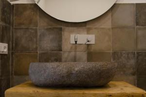 a bathroom with a stone sink and a mirror at Garibaldi Rooms, Boutique Stay in Val di Noto with Piazza & Church Views in Rosolini