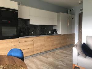 eine Küche mit weißen Schränken, einem Tisch und einer Couch in der Unterkunft Apartament Victoria 5 Mórz in Sianożęty