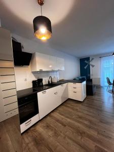 eine Küche mit weißen Schränken und einer schwarzen Arbeitsplatte in der Unterkunft Studio Mewa in Świnoujście