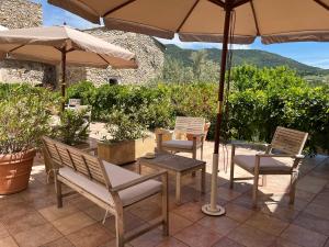 a patio with a table and chairs and an umbrella at Logis Hôtel La Bastide des Monges in Nyons