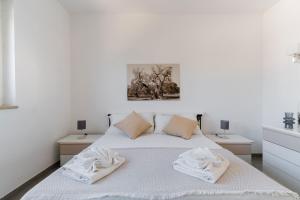 a white bedroom with a bed with towels on it at Attico Mezzaluna by BarbarHouse in Torre Santa Sabina +39 photos