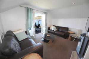 Una sala de estar con un sofá de cuero y un televisor. en The Inn on the Loch, en Castle Douglas