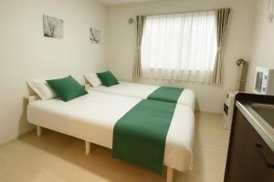 a bedroom with a large white bed with green pillows at Niseko Yotei Vista in Kutchan