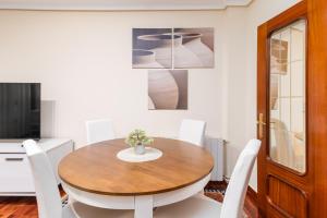 Un comedor con una mesa de madera y sillas blancas. en Apartamento PEDREGAL en el CASCO HISTÓRICO, en Castro Urdiales