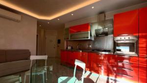 een keuken met rode kasten en een glazen tafel bij Olimpia in Arma di Taggia