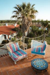 2 Stühle und ein Tisch auf einer Terrasse mit einer Palme in der Unterkunft Monte Meu in Odemira