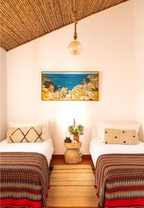 ein Schlafzimmer mit zwei Betten und einem Gemälde an der Wand in der Unterkunft Monte Meu in Odemira