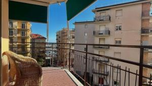 een balkon met een rotan stoel en gebouwen bij Olimpia in Arma di Taggia