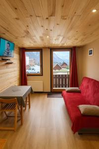 a living room with a red couch and a table at Le Bois Joli en Chartreuse in Saint-Pierre-de-Chartreuse