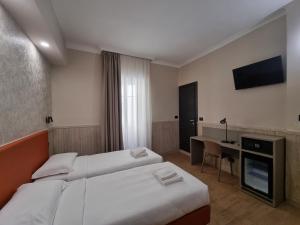 a hotel room with two beds and a desk at Hotel Pyramid in Rome