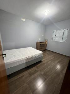 a bedroom with a white bed and a wooden floor at Casa Refúgio interior -SP in São Miguel Arcanjo