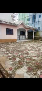 Villa de luxe LE HAVRE DE JOIE ET DE PAIX 300m2 de superficie Wifi illimité forage et grande cour pour garer plusieurs voitures ou organisation celebrations في دوالا: مبنى به ساحة حجرية كبيرة أمام مبنى آخر