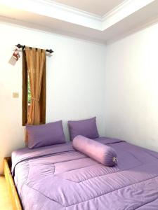 Sokkyo Homestay Kaliurang في Ngemplak: سرير أرجواني في غرفة مع نافذة