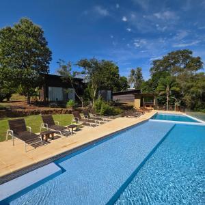 a swimming pool with lounge chairs next to a house at Tupa Lodge Selva y Rio in Puerto Iguazú