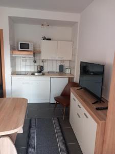 een kleine keuken met witte kasten en een televisie bij Ferienwohnungen Albinshof in Krien +3 foto's