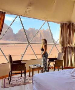 ein kleines Mädchen steht in einem Raum mit einem großen Fenster in der Unterkunft BUBBLE lUXURY RUM JNOPE CAMP in Wadi Rum + 39 Fotos