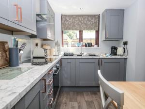 a kitchen with gray cabinets and a wooden table at Dolly Blue in Ulverston +14 photos