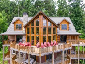 Una cabaña de troncos con una terraza envolvente con sillas rojas. en Hidden Ridge, en Boone