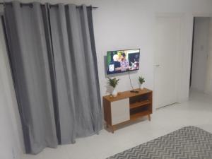 a tv sitting on a stand in a room with curtains at AP aconchego de Ilhéus in Ilhéus