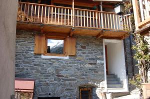 a stone building with a window and a wooden balcony at Case Gran Paradiso Rhemes Saint Georges Vieux in Rhemes-Saint-Georges