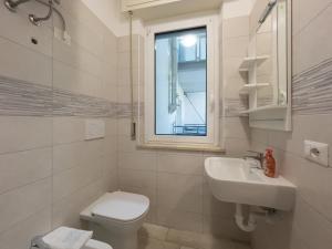 a bathroom with a toilet and a sink and a window at Sunbeach Apartments in Lignano Sabbiadoro +39 photos