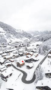 Un pequeño pueblo cubierto de nieve con una carretera. en CHALET CHARMING BED and BREAKFAST, en Les Gets