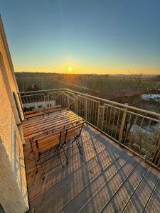 盖森费尔德Bavaria Home - Zentral, Küche, Waschen, Parken的夕阳西下，映照着阳台上摆放的长椅和木质平台。