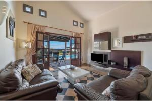 ein Wohnzimmer mit einer Ledercouch und einem Tisch in der Unterkunft Villa Tania - Villa independiente con piscina privada in Playa Blanca