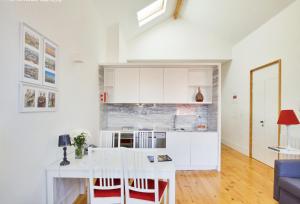 a kitchen with white cabinets and a table with chairs at Charming Apartments in Historic Centre - Inside Porto Apartments "Flores" in Porto +8 photos