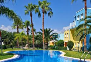 una piscina con palmeras frente a un edificio en Apartamento Acuarela by Family Homes, en El Verger