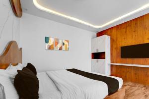 Vānivilāsa PuramHotel O Udaya Residency的卧室配有白色的床和墙上的电视