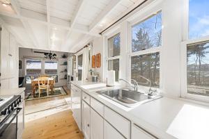 a kitchen with white cabinets and a sink and windows at Berrywood Cottage in Lakeside