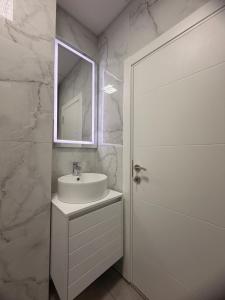 a white bathroom with a sink and a mirror at CS Apartment in Skopje