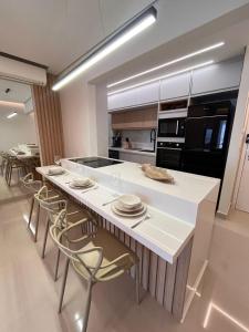 uma cozinha com uma grande ilha branca com cadeiras em Apartamento a 500m da praia de Bertioga em Bertioga