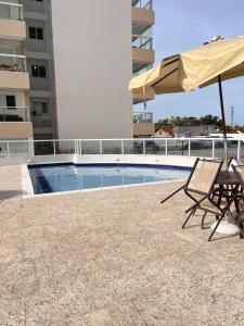 um pátio com guarda-sol e cadeiras e uma piscina em Apartamento a 500m da praia de Bertioga em Bertioga