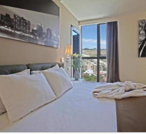 a bedroom with a white bed with a large window at Pegass hotel in Yerevan