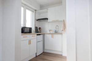 a white kitchen with white cabinets and a window at Studio le Goya - Cosy & Lumineux in Thionville